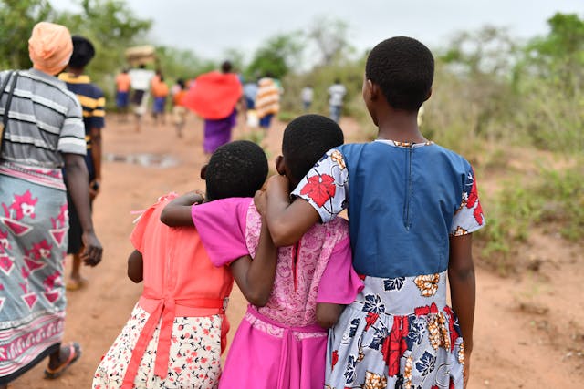 three, black girls with shaved heads wuth theur backs to the camera and ahnds over each others' shoulders